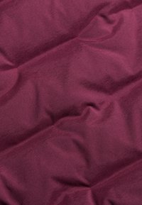 Burgundowy materiał o gładkiej fakturze, z delikatnymi zmarszczkami i miękkim połyskiem. Tkanina wydaje się lekka i elastyczna.