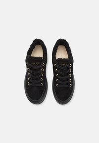 Schwarze Wildledersneaker mit Kunstfellkragen. Goldene Ösen, schwarze Schnürsenkel und eine strukturierte Außensohle. GANT-Branding auf der Zunge.
