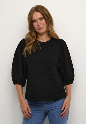 Black textured top with puffed sleeves, crew neckline, and elastic cuffs. Paired with blue jeans, featuring a subtle geometric pattern.