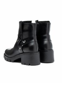 Czarne skórzane botki za kostkę z zaokrąglonym noskiem i średnim obcasem typu słupek. Posiadają boczny zamek błyskawiczny oraz ozdobny pasek z metalowymi akcentami.