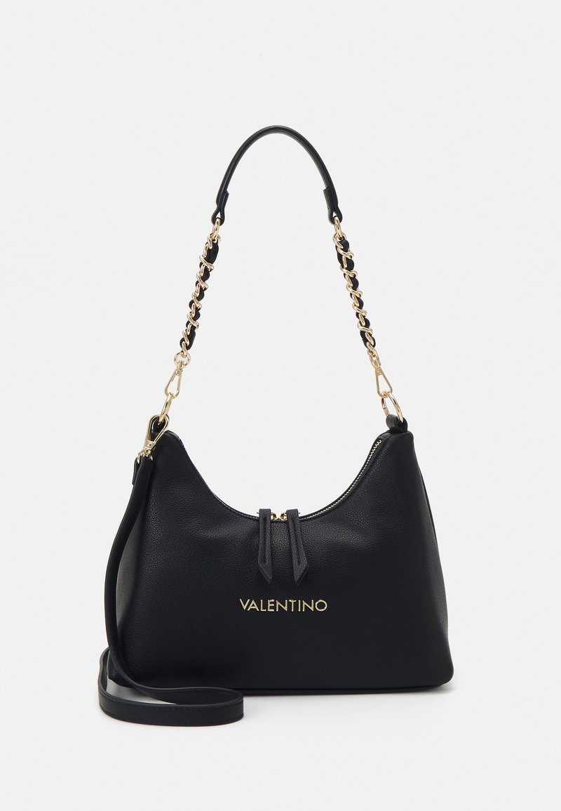 Borsa a mano in pelle nera con hardware dorato, chiusura con zip e una corta tracolla a catena. Presenta un logo impresso e una superficie liscia.