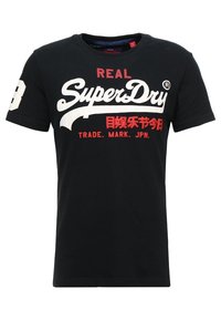 Černé bavlněné tričko s bílým a červeným textem se značením „REAL SuperDry“ a dekorativními grafikami. Krátké rukávy s detaily čísla 8.