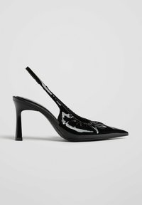 Escarpin slingback en cuir verni noir avec bout pointu et talon incurvé de hauteur moyenne sur fond uni.