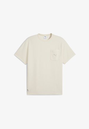 Kortermet beige t-skjorte laget av teksturert stoff. Har en lomme på venstre bryst og en liten logo på kanten. Klassisk rund hals.