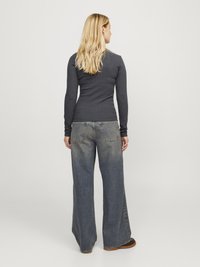 Langermet, mørkegrå ribbestrikket topp sammen med løstsittende blå denimjeans med en falmet finish og store lommer, med rett ben-design.