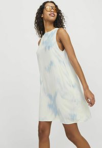 Ärmlös A-linje klänning i ljusgul tyg med ett blått abstrakt mönster. Slät textur, knälång, med en avslappnad passform.