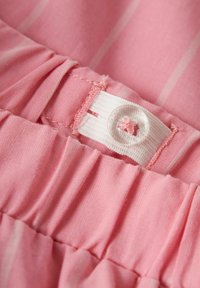 Tissu rose avec des rayures subtiles, doté d'une taille élastique blanche et d'un bouton transparent avec une accent en forme de fleur rose cousu au-dessus.