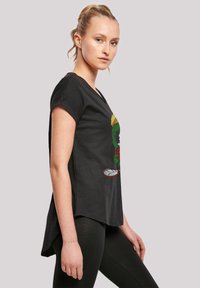 Svart bomull T-skjorte med et fargerikt tegneseriefigur-grafikk, korte ermer og en litt lengre bakhem, parret med svarte leggings.