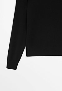 Pull noir à manches longues avec un design simple et uni et un ourlet droit, présenté sur un fond blanc.