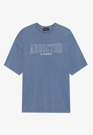 Tricou oversized albastru, fabricat dintr-un material moale, având un guler rotund. Textul de pe față spune "ADDICTED TO PARADISE" în litere albe, îndrăznețe.