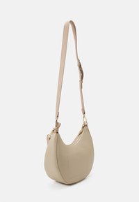 Beige läderaxelväska med en böjd form, justerbar rem och detaljer i guldton. Har ett toppfack med dragkedja och diskret sömnadsdetalj.
