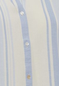 Camicia a righe blu chiaro e crema con apertura a bottoni, tessuto testurizzato e bottoni rotondi lungo la patta.