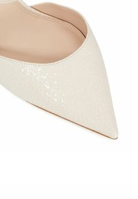Pointed-toe shoe in textured cream leather with a smooth interior and minimal stitching detail, featuring a sleek, modern silhouette.