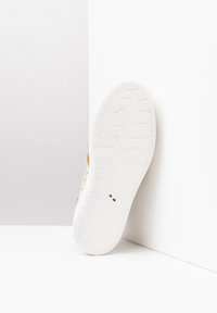 Sneaker bianco con suola in gomma texture, caratterizzato da un accento oro chiaro e una tomaia liscia con un motivo geometrico. Taglia 37 contrassegnata.