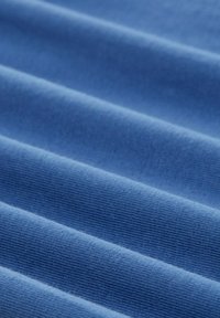 Niebieska prążkowana tkanina z poziomymi fałdami, ukazująca teksturę i miękką jakość materiału w zbliżeniu.