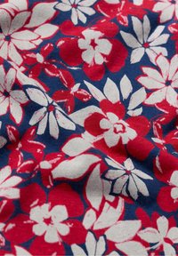 Floral fabric featuring red and white flowers on a dark blue background. The texture appears soft with a slight sheen.