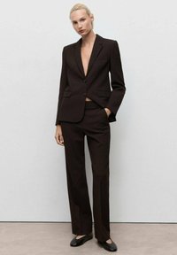 Brown tailored suit, featuring a single-button blazer with notch lapels and flat-front trousers. Smooth fabric and minimalist design.