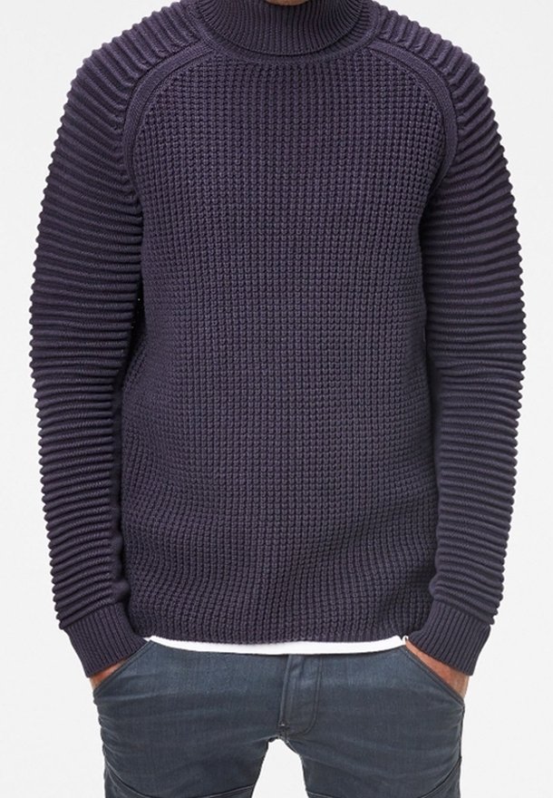 Mörkblå stickad tröja med hög krage, med texturerad ribbning på ärmar och kropp, samt en figurnära silhuett.
