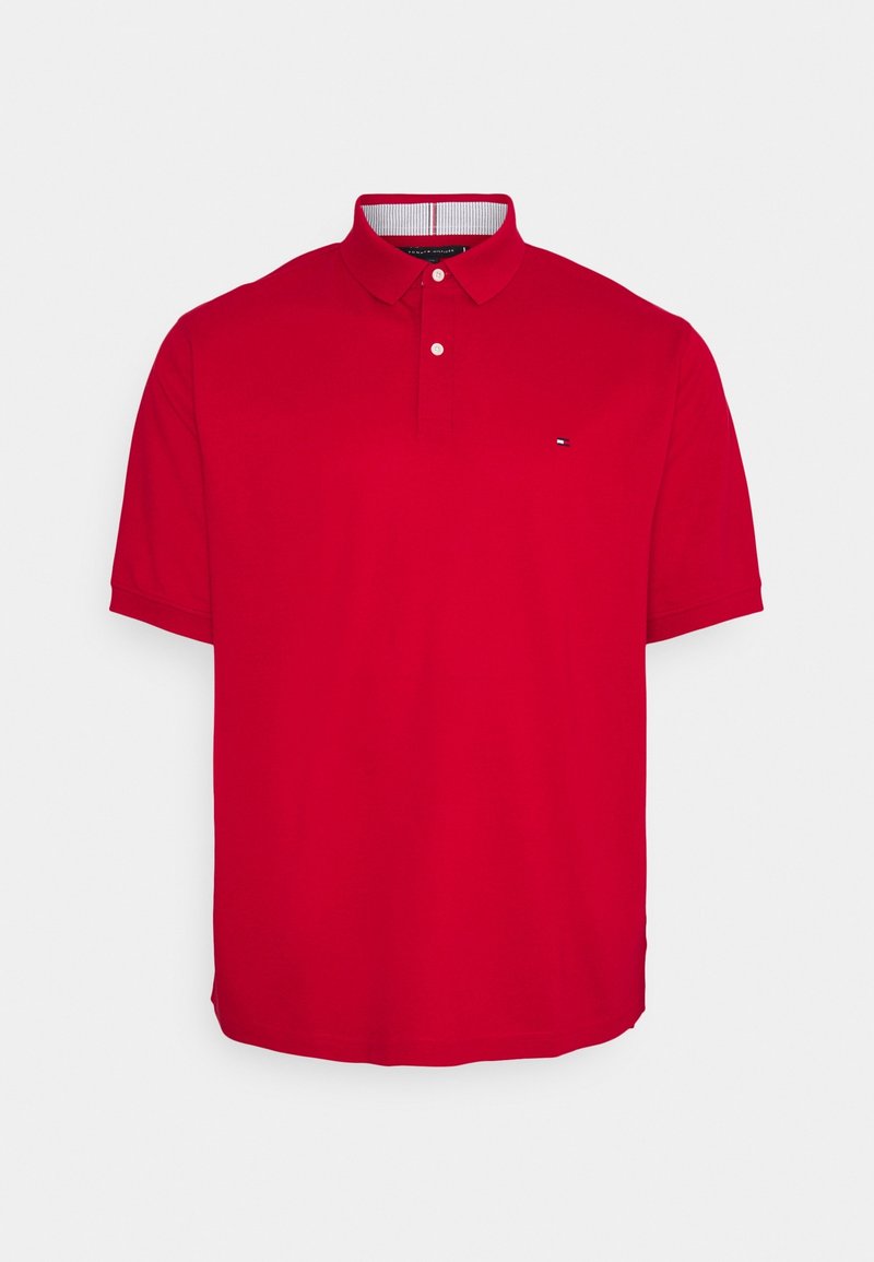 Polo rouge à manches courtes avec col à boutons et petit logo sur la poitrine gauche, présenté sur un fond gris clair uni.