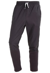 Svarta träningsbyxor med dragsko i midjan, avsmalnande ben och kontrasterande textil vid nedre benen.