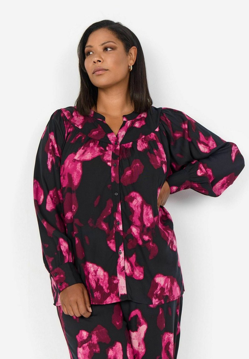 Blusa nera con motivo floreale astratto rosa, maniche lunghe a sbuffo, chiusura frontale a bottoni e scollo rotondo. Tessuto leggero con un leggero brillante.