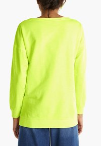 Sudadera de manga larga de un brillante color amarillo neón con un corte holgado, cuello redondo, puños y dobladillo acanalados, que presenta un aspecto casual y texturizado.