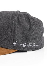 Gray wool blend cap with a brown suede visor. Features white embroidered text along the side. Soft texture with a rounded crown design.