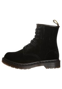 Černé semišové kotníkové boty s kulatou špičkou, prošíváním ve vzoru, gumovou podrážkou a poutkem na patě. Texturovaný povrch dodává hloubku.