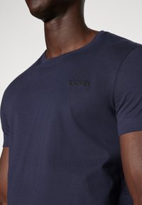 Námornícky modré tričko s kruhovým výstrihom, s jemne vyšitým logom "BORG" na hrudi. Vyrobené z hladkej, ľahkej tkaniny.