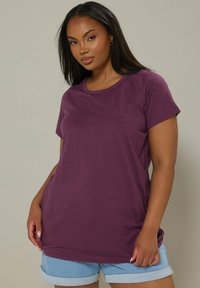 Lilla kortærmet T-shirt med rund halsudskæring, lavet af blødt stof, parret med lyse denimshorts. Glat tekstur, afslappet pasform.