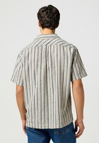 Korte mouwen shirt in een beige en blauwe verticale gestreepte patroon, gemaakt van lichte stof; heeft een kraag en een rugplooidetail.