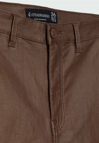 Bruine katoenen blendbroek met een gladde textuur, ritssluiting en een merklabel. Kenmerkt een knoopsluiting en een standaard vijf-pocket ontwerp.