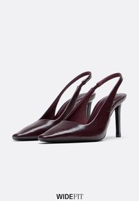Tacchi slingback in pelle verniciata bordeaux con punta affilata e sottile tacco a spillo nero. La parte superiore testurizzata presenta dettagli di finitura sottili.
