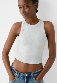 Gray ribbed tank top with a high neckline and sleeveless design, paired with blue denim shorts. The fabric appears soft with a fitted shape.