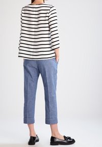 Černobílé pruhované dlouhé rukávy, světle modré zkrácené kalhoty a černé mokasíny s mašlí, které představují jednoduchý, neformální vzhled.