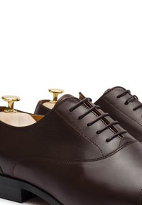 Scarpe da cerimonia in pelle marrone con finitura liscia, dotate di un design con lacci, punta tonda e forme per scarpe in tonalità dorata all'interno.