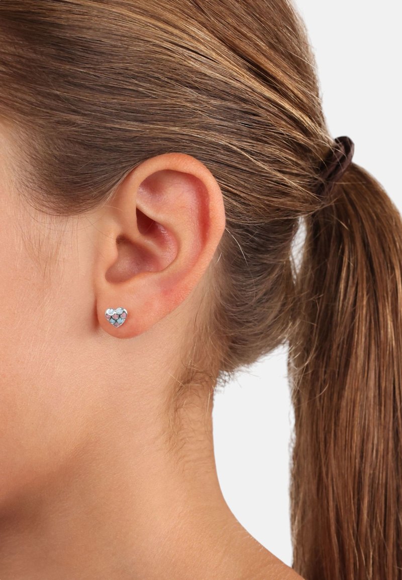 Orecchini a perno a forma di cuore con pietre preziose blu e trasparenti incastonate in una montatura metallica. Il design è piccolo e adatto per l'uso quotidiano.