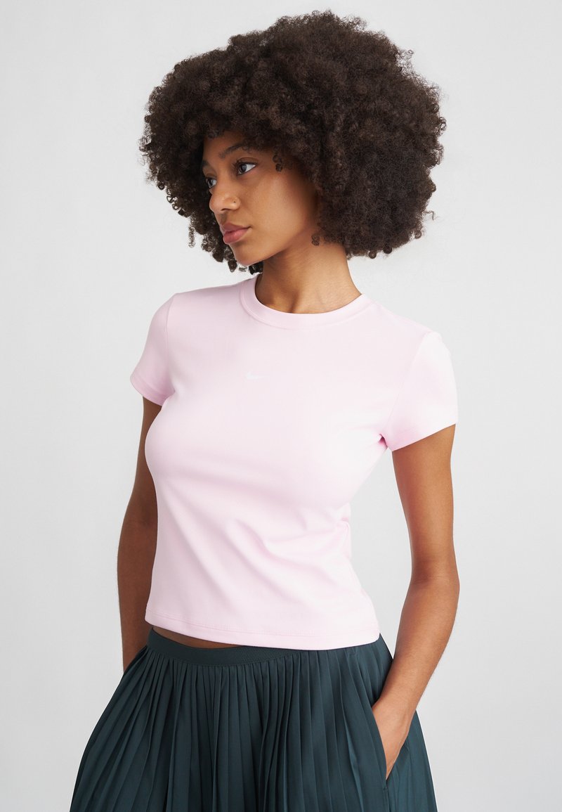 Różowa, dopasowana koszulka z okrągłym dekoltem i krótkimi rękawami, wykonana z gładkiego materiału; posiada dyskretną białą grafikę na piersi.