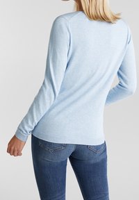 Vaaleansininen neulepusero, jossa pitkät hihat, pyöreä pääntie, ribbineulotut hihansuut ja helma, pehmeä tekstuuri, yhdistetty istuviin sinisiin farkkuihin.