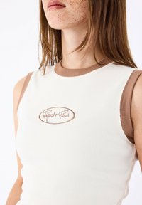 Canotta bianca a coste con scollatura rotonda e fori per le braccia marroni. Presenta un logo ricamato "Project Paris" in una tonalità di marrone abbinata.