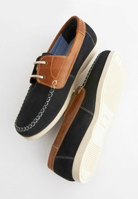 Scarpe da uomo bicolore in suede blu navy con dettagli in pelle marrone; presentano un design con lacci e una suola in gomma texturizzata.