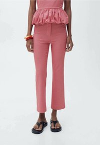 Rode gingham peplum top met gerimpelde zoom, gecombineerd met slim-fit rode geruite broek. Model draagt platte zwarte sandalen.