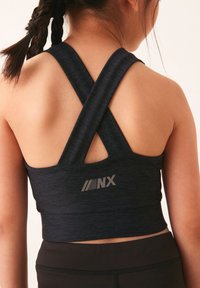 Sort træningstop med krydsede stropper, tekstureret stof og et logo på ryggen. Velegnet til atletiske aktiviteter.