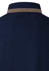 Cuello de camisa azul marino con un detalle en ante color marrón claro a lo largo del borde. Textura suave con costuras estructuradas y sin patrones adicionales.