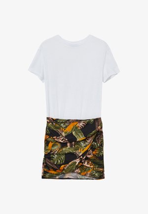 T-shirt en coton blanc à manches courtes, associé à une jupe noire ornée d'un motif de feuilles tropicales vertes et oranges, froncée à la taille.