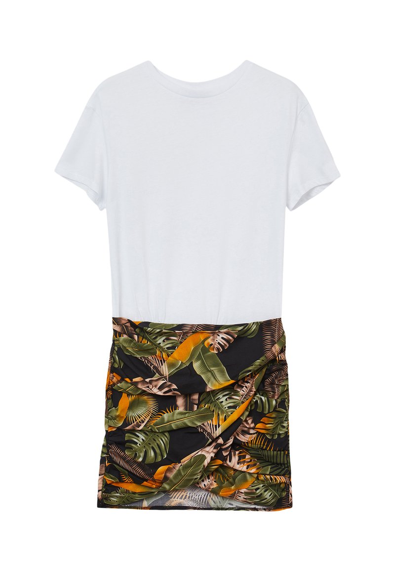 T-shirt bianca di cotone con maniche corte, abbinata a una gonna nera con un motivo di foglie tropicali in verde e arancione, arricciata in vita.