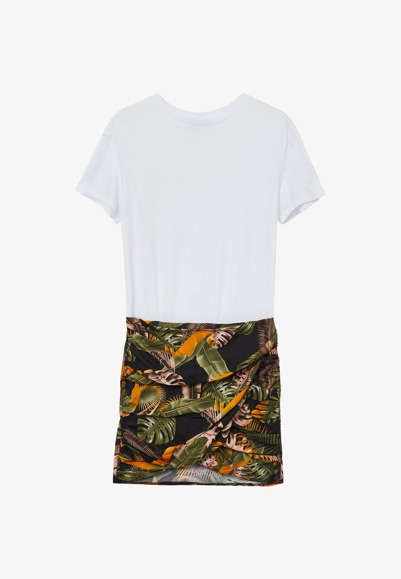 Weißes Baumwoll-T-Shirt mit kurzen Ärmeln, kombiniert mit einem schwarzen Rock, der ein tropisches Blattmuster in Grün und Orange zeigt und an der Taille gerafft ist.