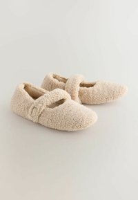 Béžové plyšové pantofle s měkkým, strukturovaným povrchem, zaoblenou špičkou a ozdobným páskem přes nárt.