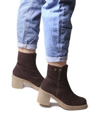 Stivaletti in suede marrone con punta arrotondata e zip laterale. Presentano un tacco spesso e texturizzato e una suola piatta beige.