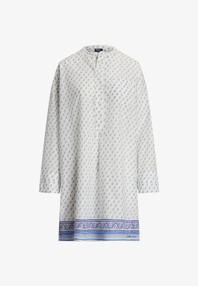 Tunique blanche à manches longues avec petit imprimé floral bleu et bordure bleue à motifs le long de l'ourlet et du col sans col.